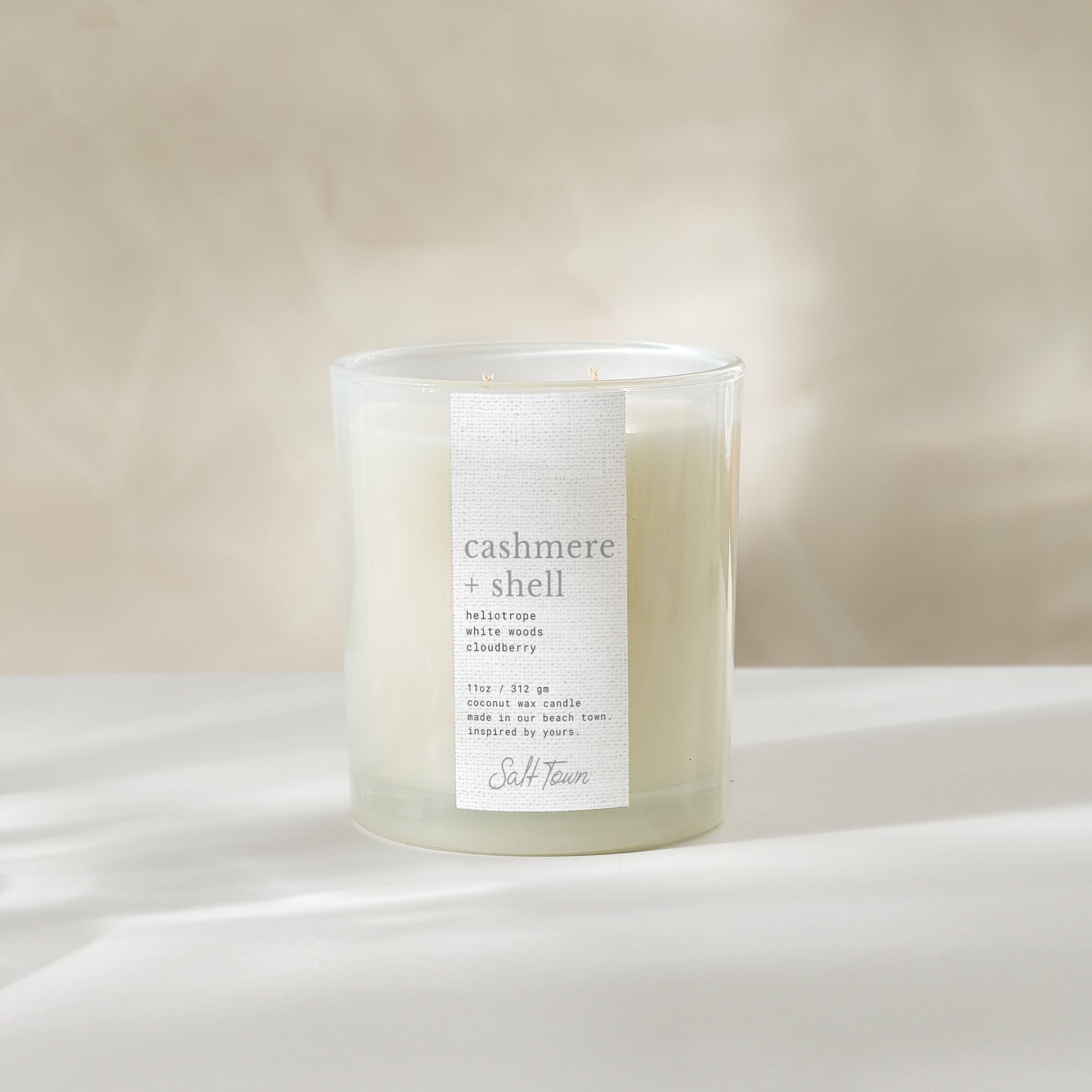 Cashmere Shell candle on a white surface with a neutral background.