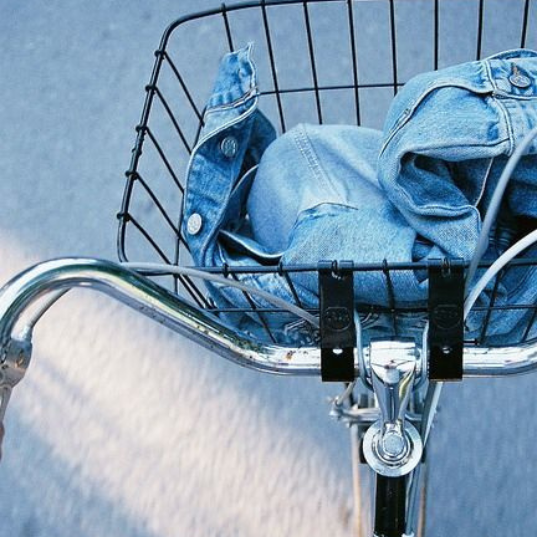 Bicycle basket with a denim jacket on a light blue background
